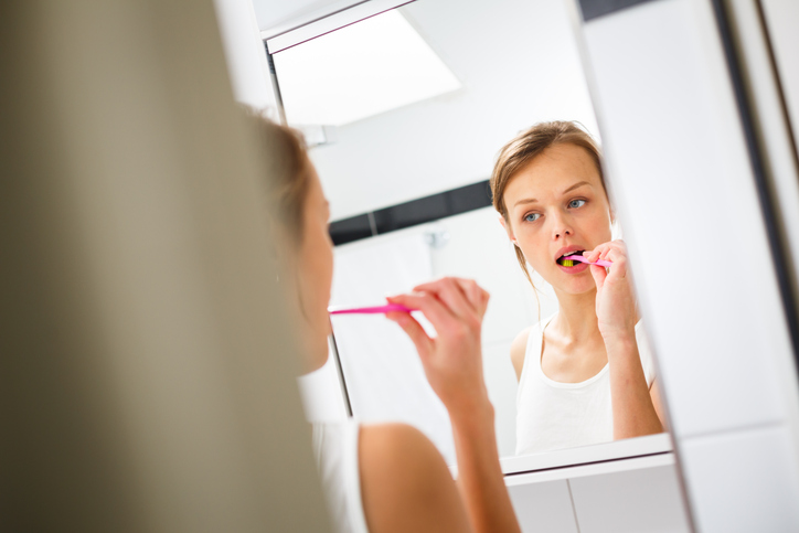 Female brushing her teeth in the mirror